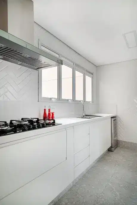 Cozinha com paredes em revestimento de escama de peixe de cor branca. Moveis brancos.