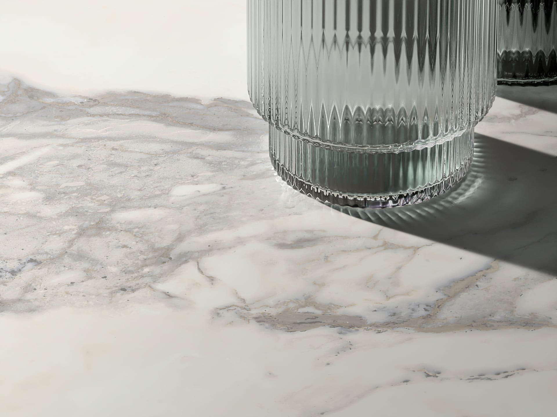 Superfície com porcelanato calacata da Portobello e um copo.