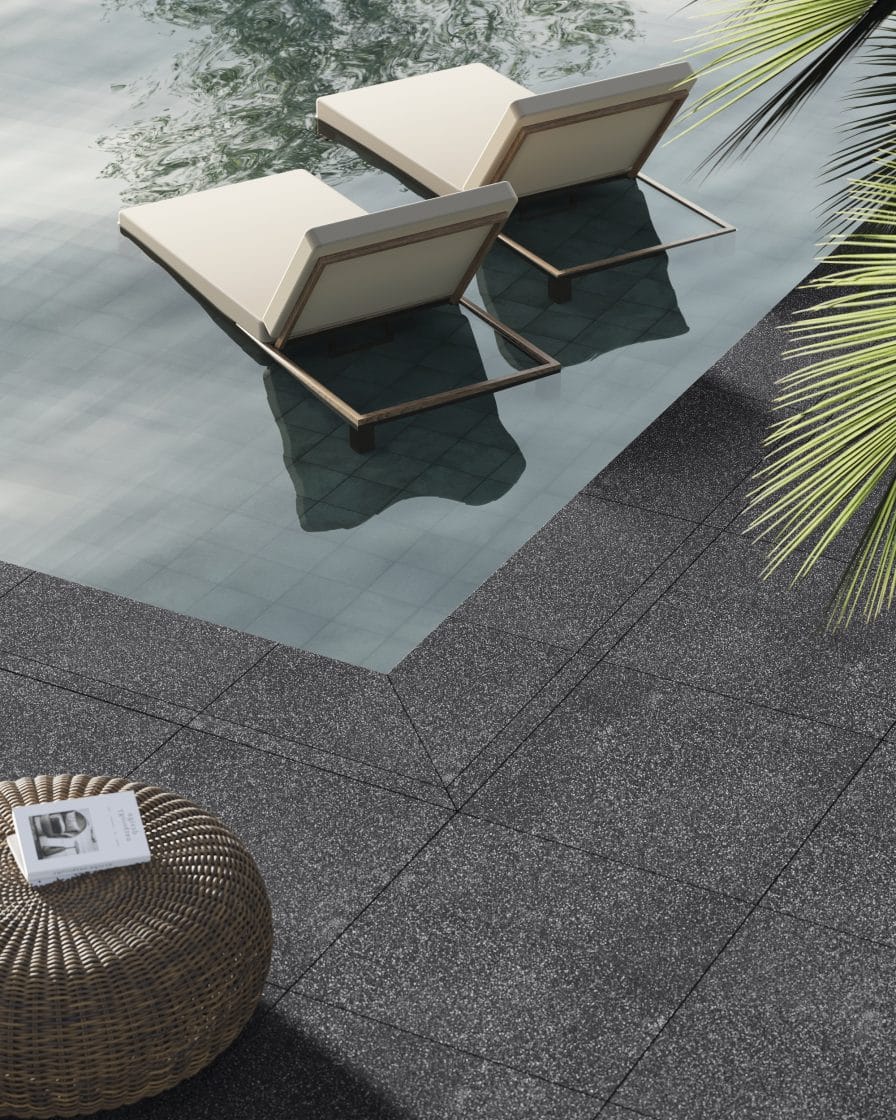 Detalhe da borda de uma piscina com revestimento acinzentado e duas cadeiras.