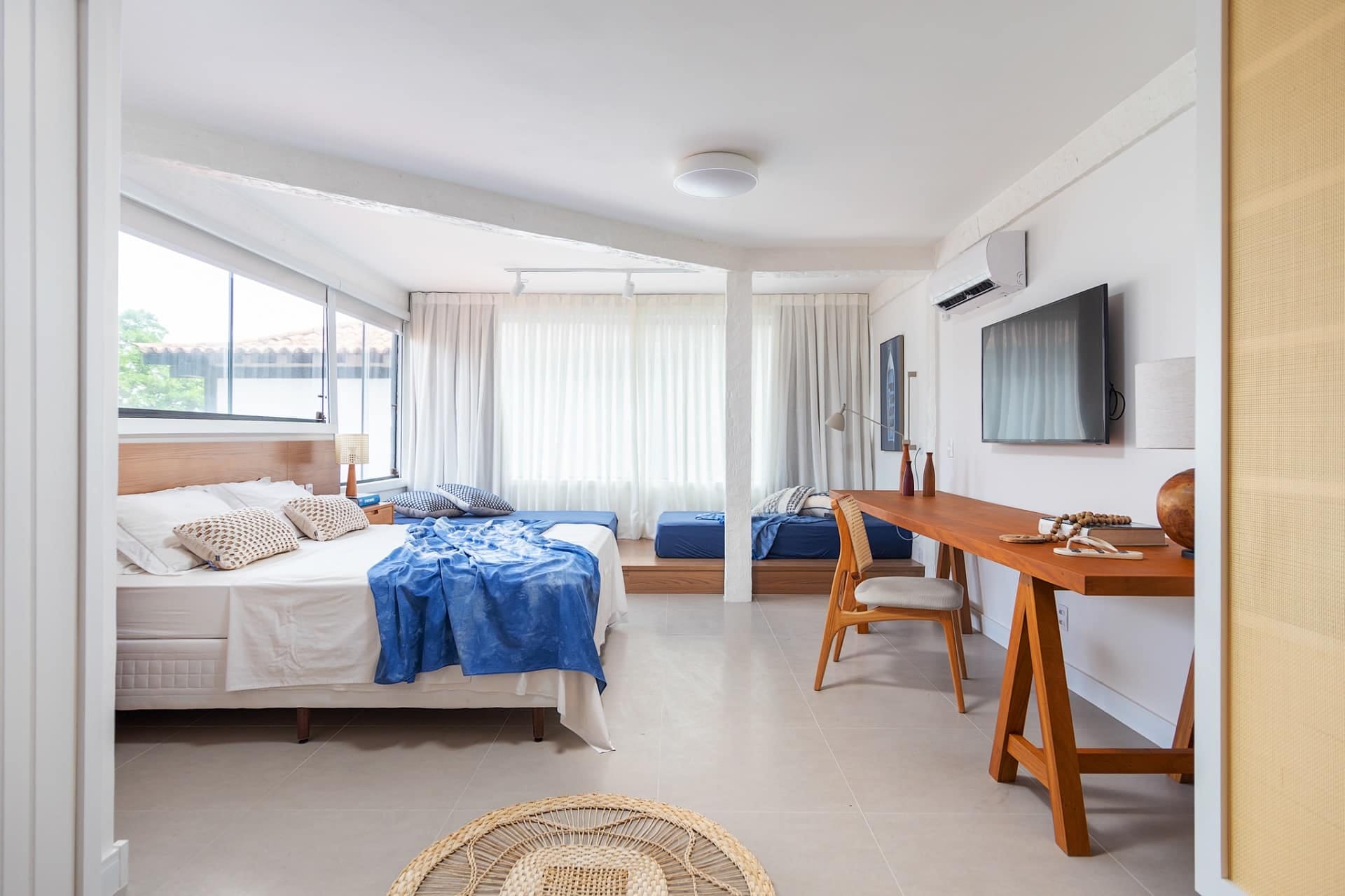 Quarto de casal em casa de praia, com tons neutros e detalhes em azul e madeira