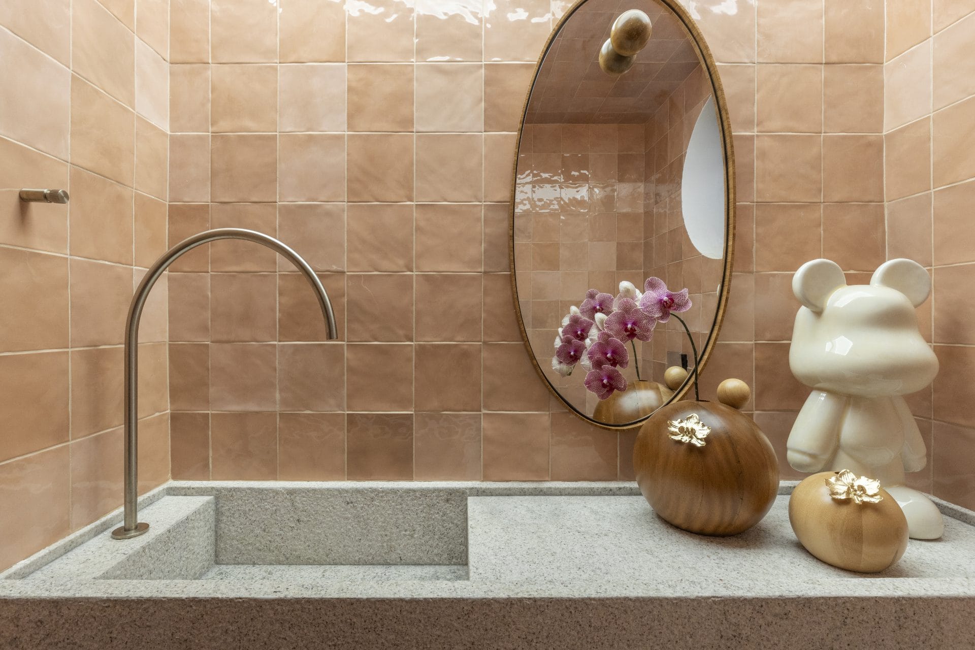 Bancada de banheiro com revestimento cor pêssego ao fundo