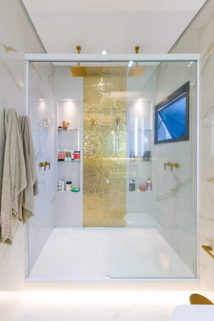 Contraste entre o revestimento escuro e os tons claros de Oro Bianco. As fotos de banheiro deste projeto mostram como planejar o ambiente para um casal compartilhar em grande estilo.