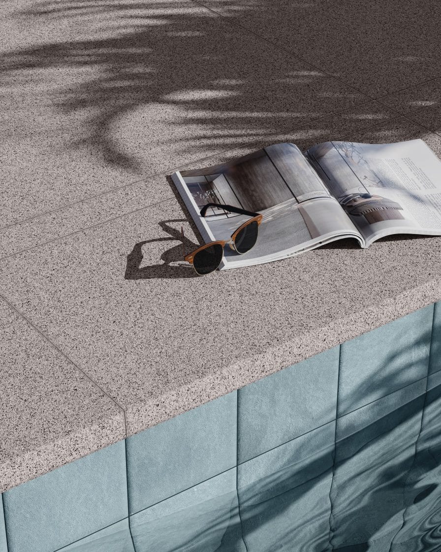 Borda de piscina. Há uma revista e um par de óculos sobre o piso (Projeto: Portobello)