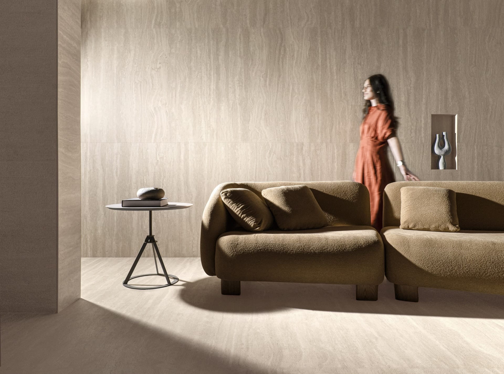 Living em tons neutros, com piso e parede em porcelanato que reproduz travertino