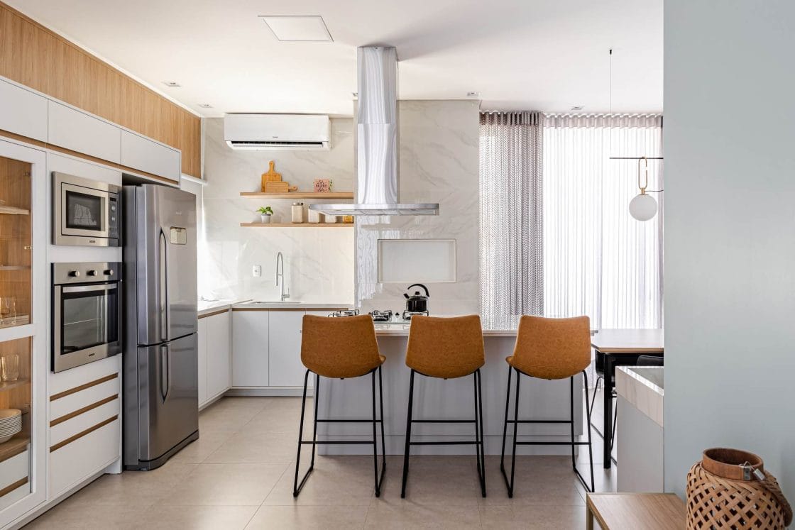 Tanto o balcão da pia quanto a ilha foram revestidos com o porcelanato marmorizado Bianco Covelano (Projeto: Karla Luize Piloneto) / Foto: Artur Pretto