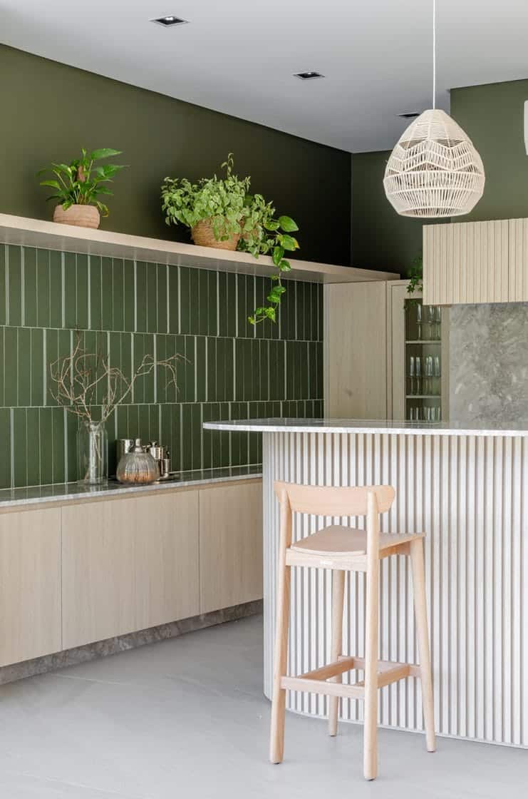 Cozinha verde e bege com elementos em madeira e planta jiboia e outras espécies de planta (Projeto: Okno Arquitetos/Foto: Fábio J. Severo)