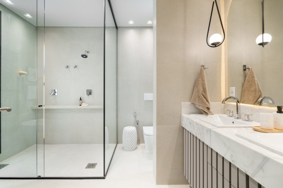 Banheiro amplo tem box em vidro que alcança duas paredes (Projeto: Caroline Rodrigues)