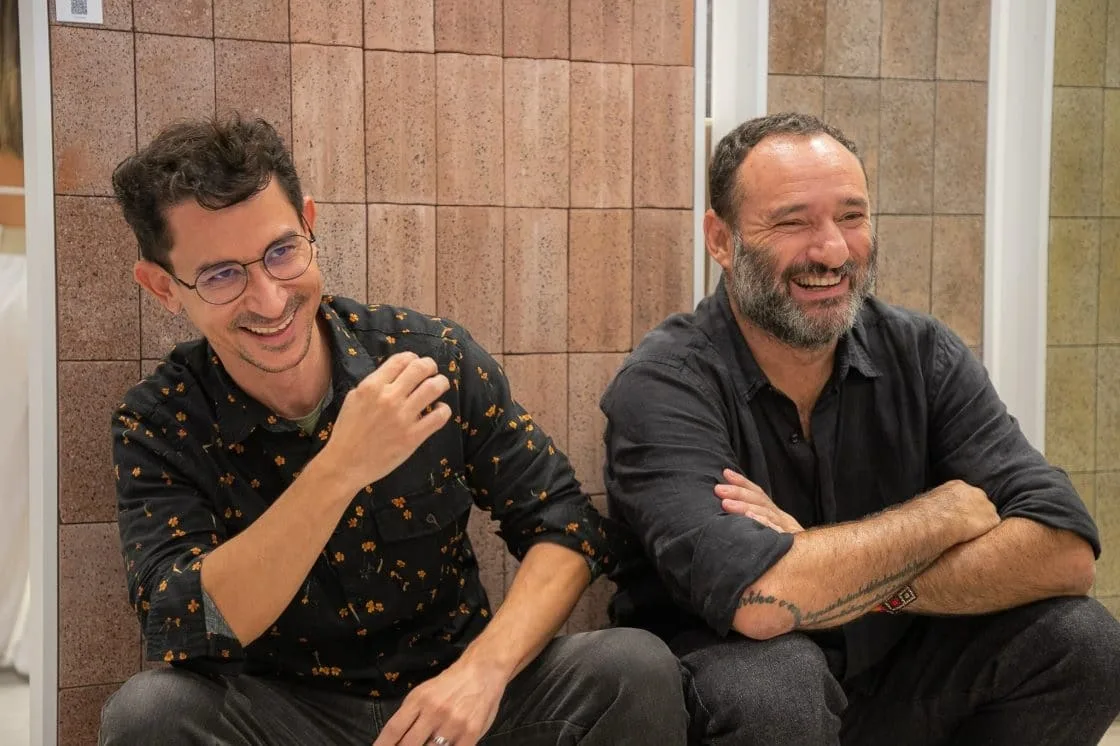 Rodrigo Ambrosio e Marcelo Rosenbaum na Expo Revestir 2024 em frente à parede com produto em colaboração com a Portobello (Foto: Guto Campos)