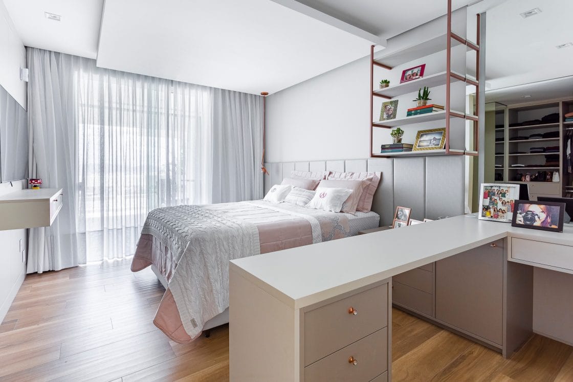 Quarto home office com bancada setorizando o quarto e cama de casal (Projeto: Trevi Arquitetura e Engenharia)