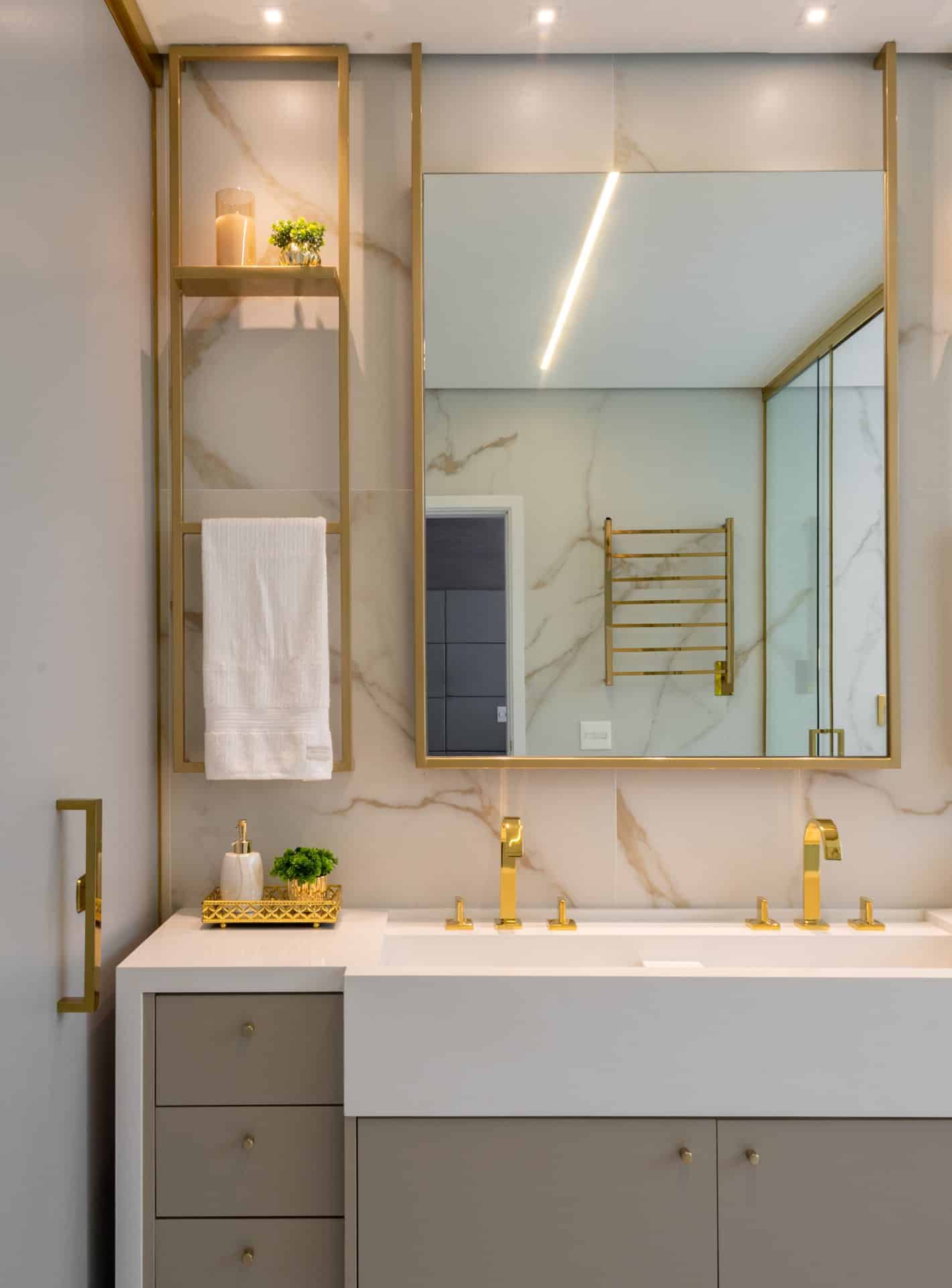 Toalheiro dourado térmico combinando com os veios dourados do revestimento marmorizado Oro Bianco, da Portobello (Projeto: Mattos Arquitetura)