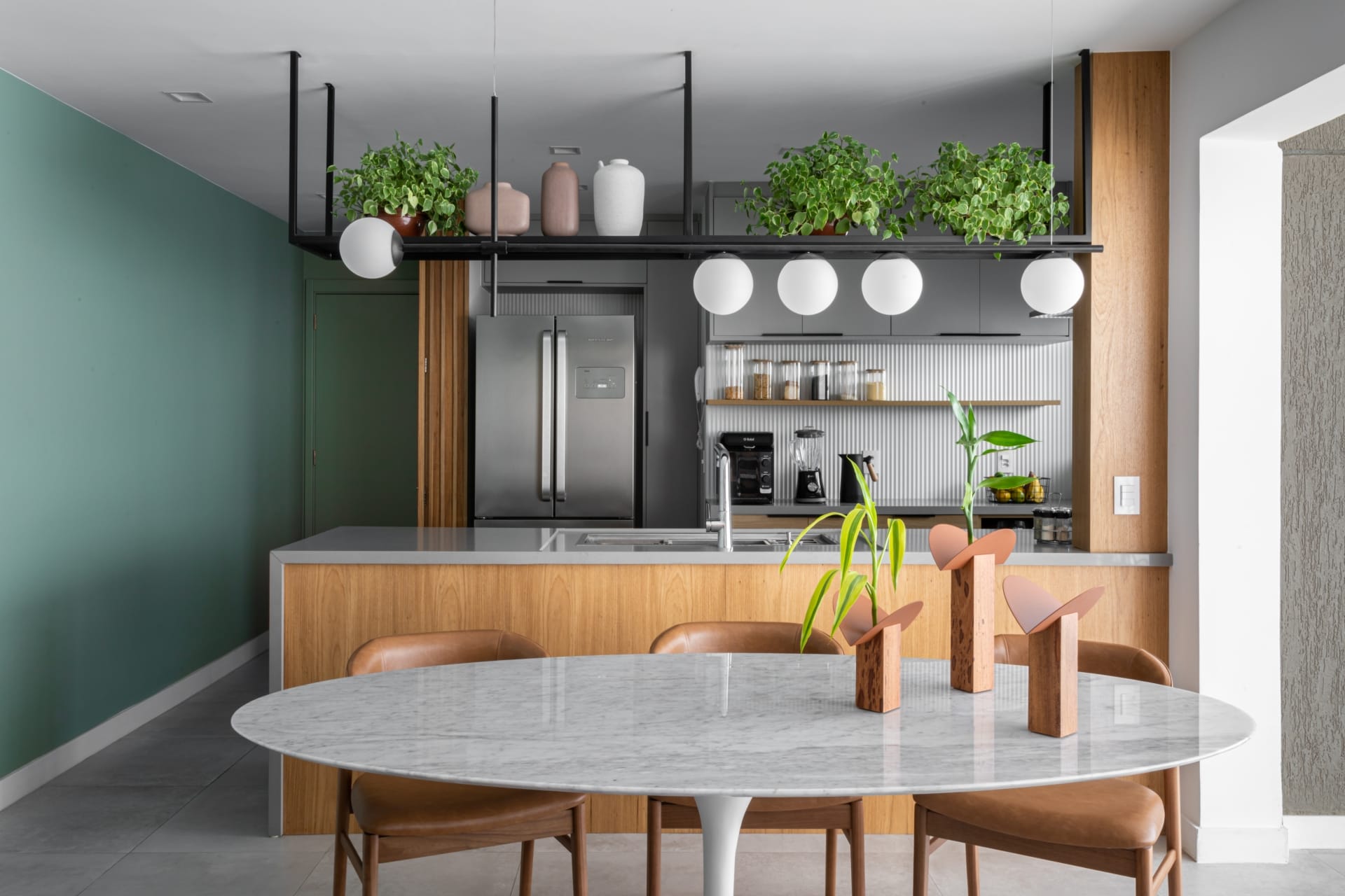 Cozinha integrada com sala de jantar com parede verde e em madeira.