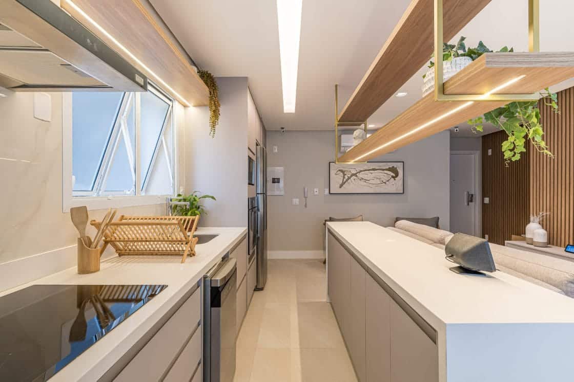 Cozinha em tons claros integrada com sala de estar, bem iluminada e com fogão de indução.