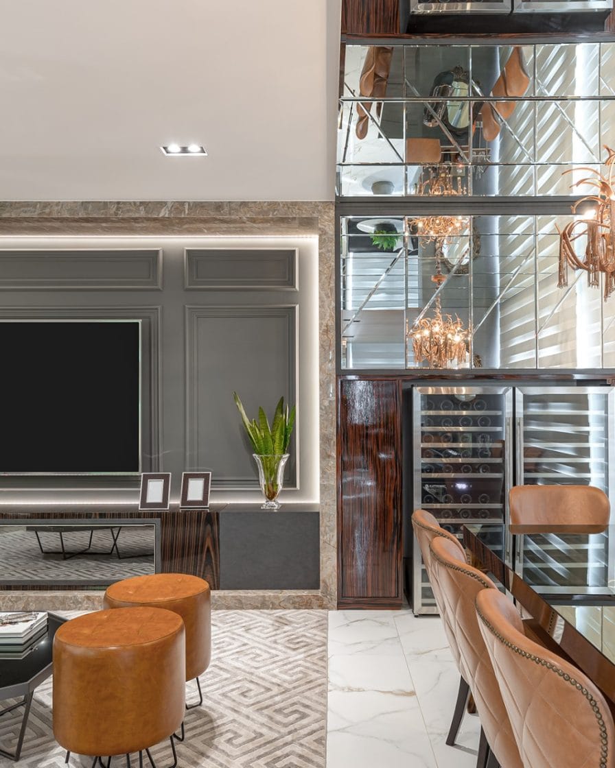 Sala integrada com muitos detalhes decorativos, inclusive um painel de TV com boiserie.