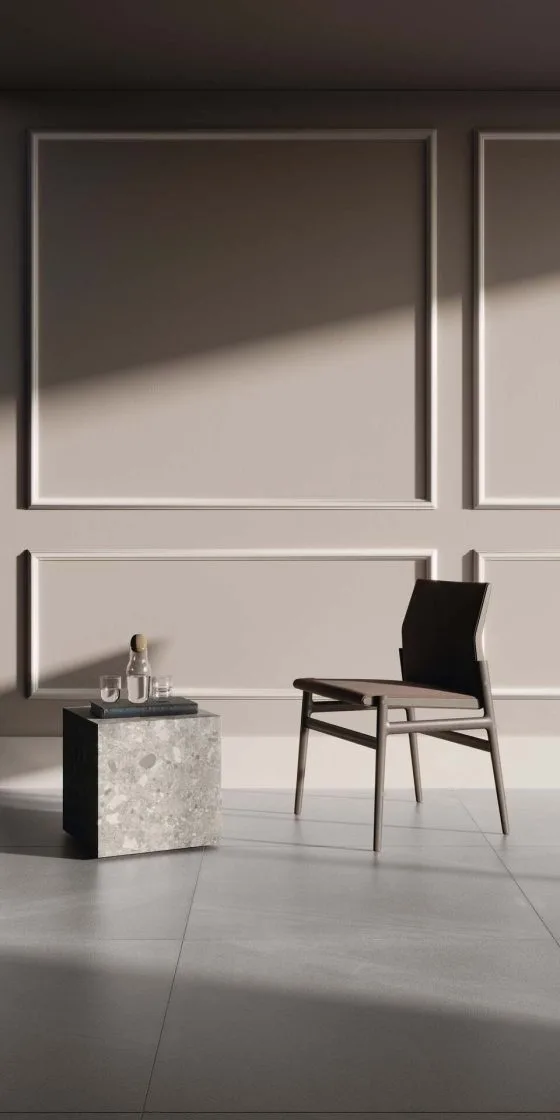Parede em tom acinzentado com detalhes de rodameios utilizados como boiserie. Há uma mesinha e uma cadeira à frente.